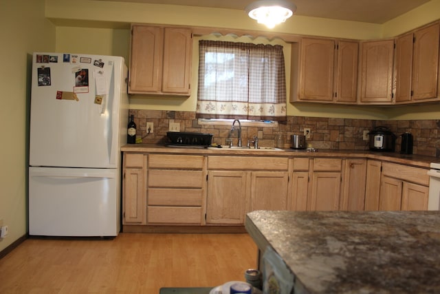 kitchen featuring light wood-type flooring, light brown cabinets, a sink, freestanding refrigerator, and decorative backsplash