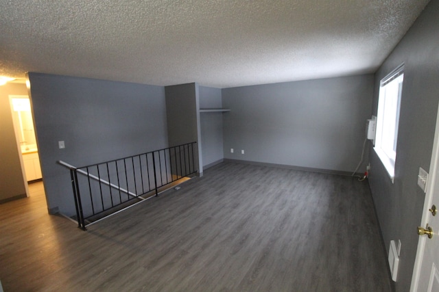 spare room with a textured ceiling and dark hardwood / wood-style flooring