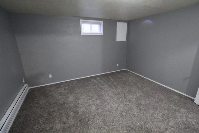 basement with a textured ceiling, a baseboard radiator, and dark colored carpet