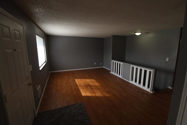 spare room featuring a textured ceiling and dark hardwood / wood-style flooring