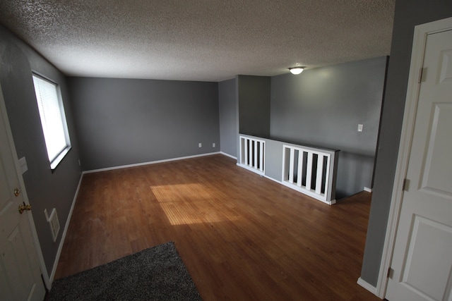 spare room with a textured ceiling and dark hardwood / wood-style flooring