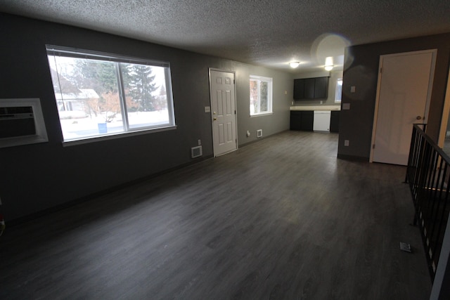 unfurnished living room featuring an AC wall unit, a textured ceiling, and dark hardwood / wood-style floors