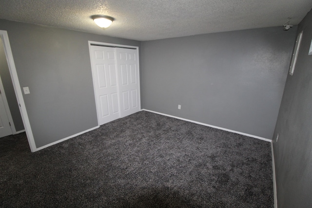 unfurnished bedroom featuring a closet, a textured ceiling, and dark colored carpet