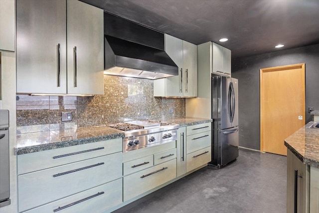 kitchen featuring stainless steel gas stovetop, fridge, wall chimney range hood, and decorative backsplash