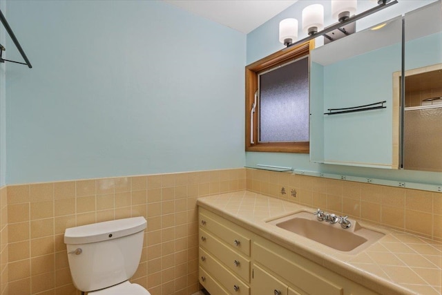 bathroom featuring vanity, tile walls, and toilet