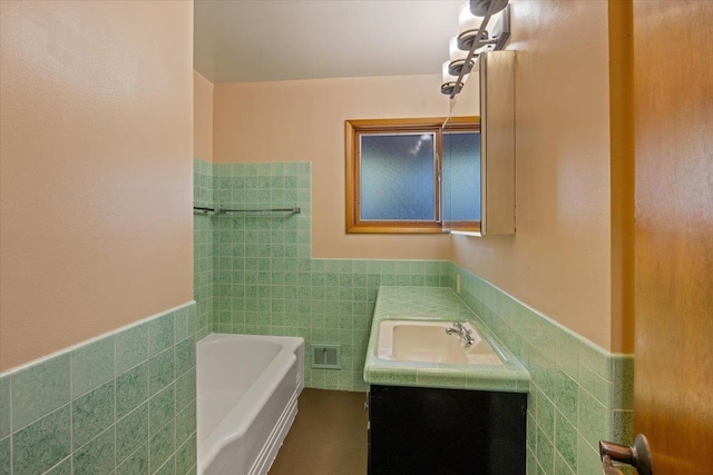 bathroom with vanity, tile walls, and a tub