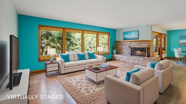 living room with a stone fireplace and light hardwood / wood-style floors