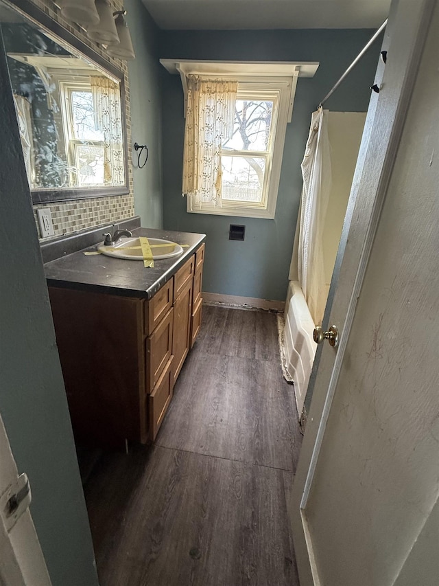 full bath featuring plenty of natural light, wood finished floors, vanity, and decorative backsplash