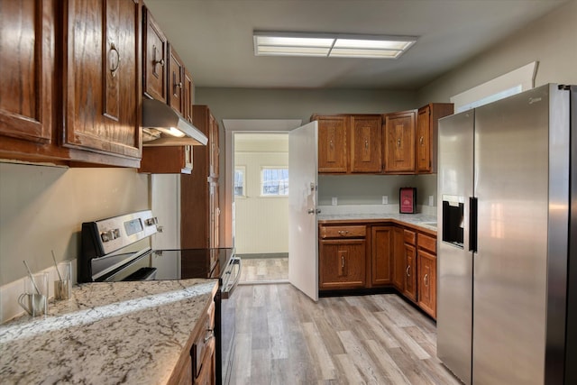 kitchen with appliances with stainless steel finishes, light stone countertops, and light hardwood / wood-style floors