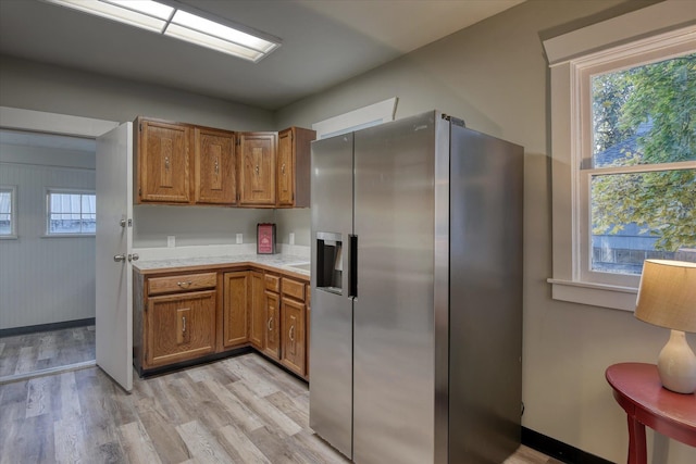 kitchen featuring a healthy amount of sunlight, light hardwood / wood-style flooring, and stainless steel refrigerator with ice dispenser