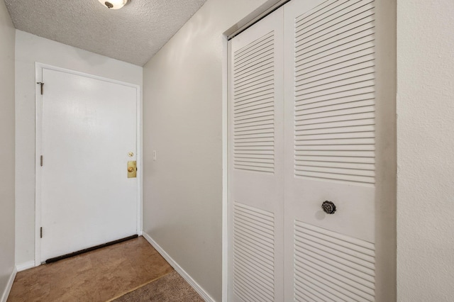 hall featuring a textured ceiling and carpet flooring