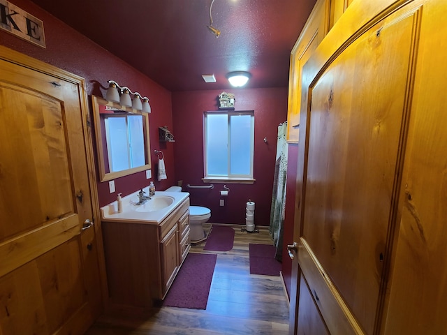 bathroom with vanity, toilet, hardwood / wood-style flooring, and a textured ceiling