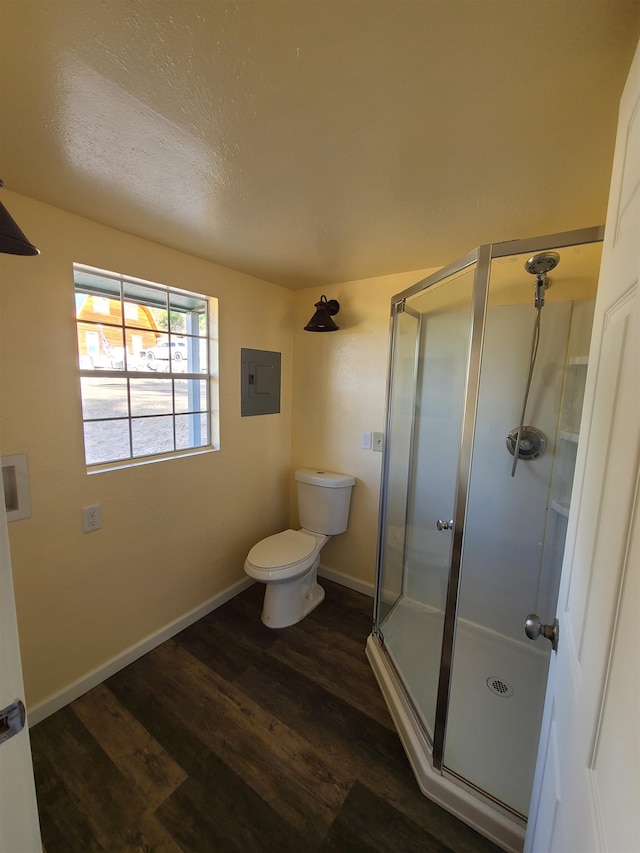 bathroom featuring toilet, electric panel, walk in shower, and hardwood / wood-style flooring