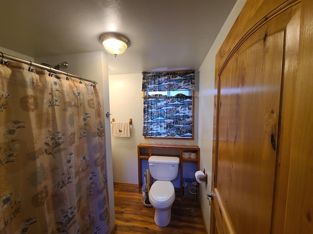 bathroom with toilet, hardwood / wood-style flooring, and walk in shower