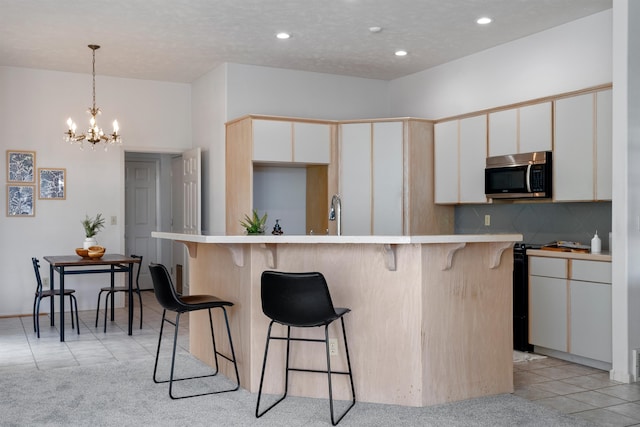 kitchen with a textured ceiling, white cabinetry, decorative backsplash, light tile patterned floors, and a chandelier