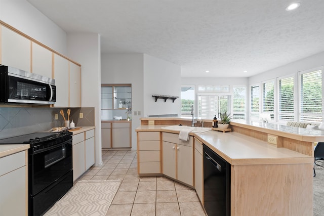 kitchen featuring a kitchen island with sink, sink, black appliances, light tile patterned flooring, and a textured ceiling