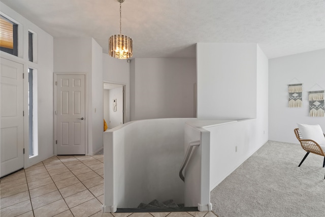 carpeted entryway with a textured ceiling and an inviting chandelier