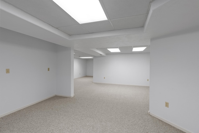 basement featuring light carpet and a drop ceiling