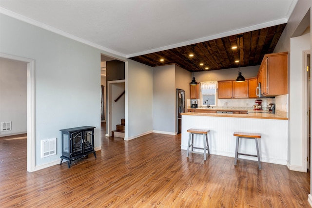 kitchen featuring a kitchen bar, a wood stove, kitchen peninsula, wooden ceiling, and hardwood / wood-style flooring