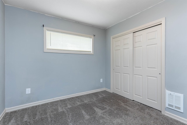 unfurnished bedroom featuring dark carpet and a closet