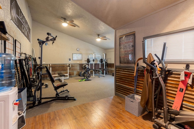 exercise room with ceiling fan, a textured ceiling, wood-type flooring, and lofted ceiling