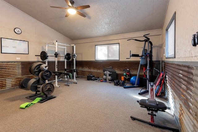 exercise room with lofted ceiling, a textured ceiling, carpet flooring, and ceiling fan