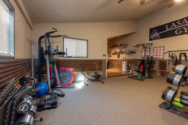 exercise room with a textured ceiling, carpet flooring, and ceiling fan