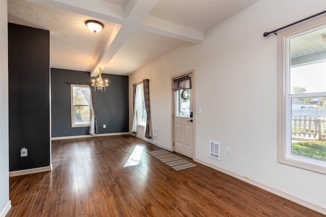 foyer entrance featuring an inviting chandelier, beam ceiling, and dark wood-type flooring