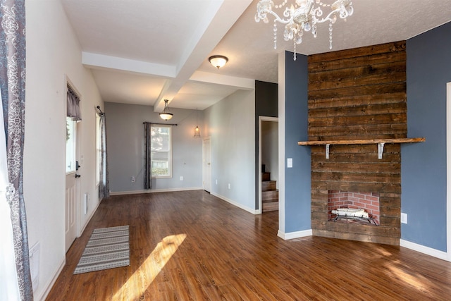 unfurnished living room with dark wood-type flooring, beam ceiling, coffered ceiling, and an inviting chandelier