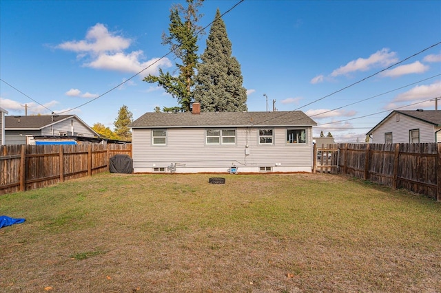 rear view of property featuring a lawn, a fenced backyard, and a chimney