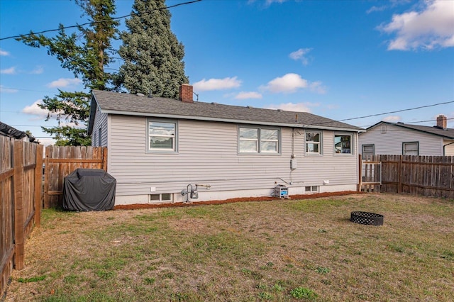 rear view of house with a lawn, a chimney, and a fenced backyard