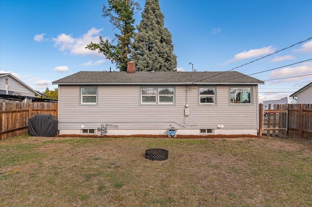 back of house with a yard, a fenced backyard, and a chimney