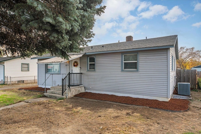 view of front of home featuring central AC unit, a chimney, and fence