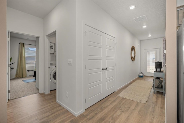 corridor featuring washer / dryer and light hardwood / wood-style flooring