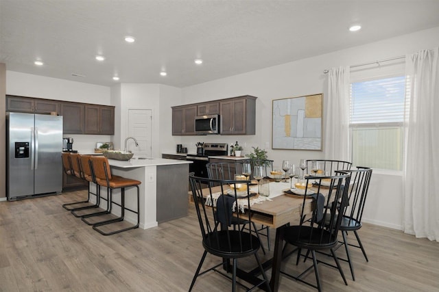 dining room featuring sink, a textured ceiling, and light hardwood / wood-style flooring