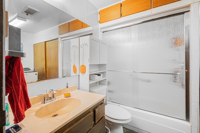 full bathroom featuring vanity, combined bath / shower with glass door, and toilet