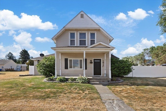 view of front of home featuring a front yard, a storage shed, covered porch, and a garage