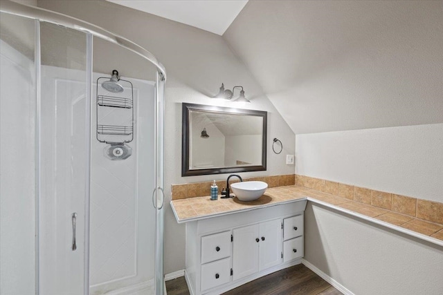 bathroom with vanity, walk in shower, wood-type flooring, and vaulted ceiling