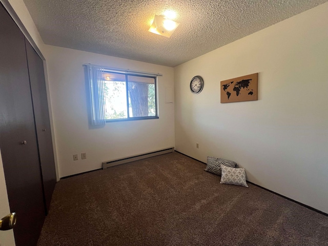 spare room featuring carpet floors, baseboard heating, and a textured ceiling