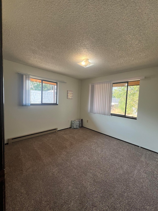 carpeted empty room with a textured ceiling and baseboard heating