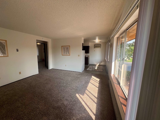 unfurnished living room with a wall mounted AC, a textured ceiling, and dark carpet