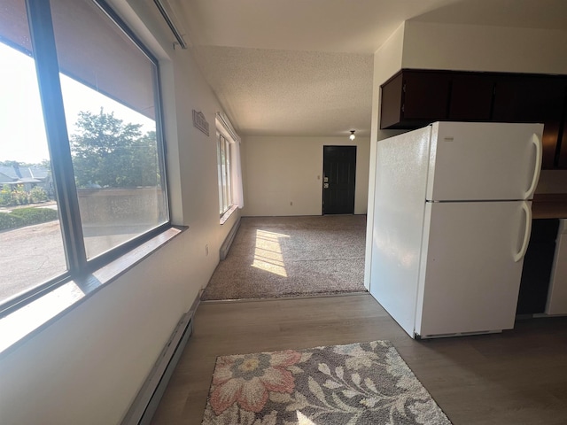 kitchen with baseboard heating, a textured ceiling, white refrigerator, and hardwood / wood-style floors