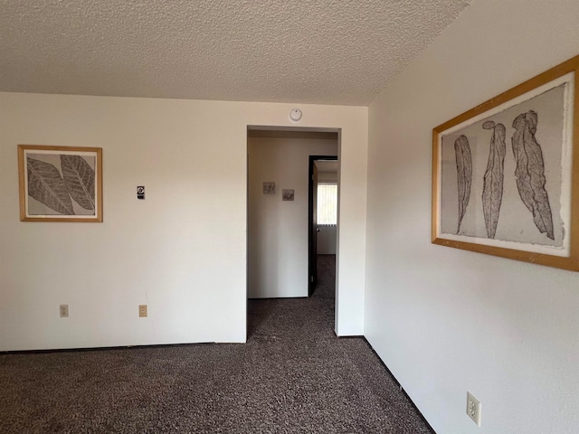 empty room featuring a textured ceiling and dark carpet