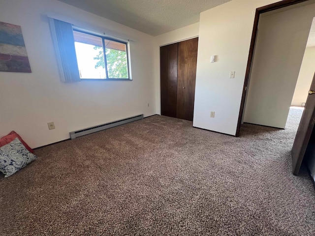 unfurnished bedroom with a closet, a textured ceiling, a baseboard heating unit, and carpet floors