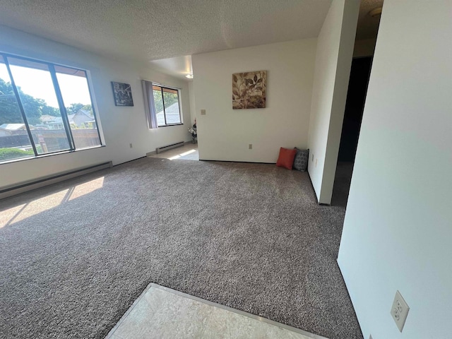 spare room featuring baseboard heating, carpet, and a textured ceiling