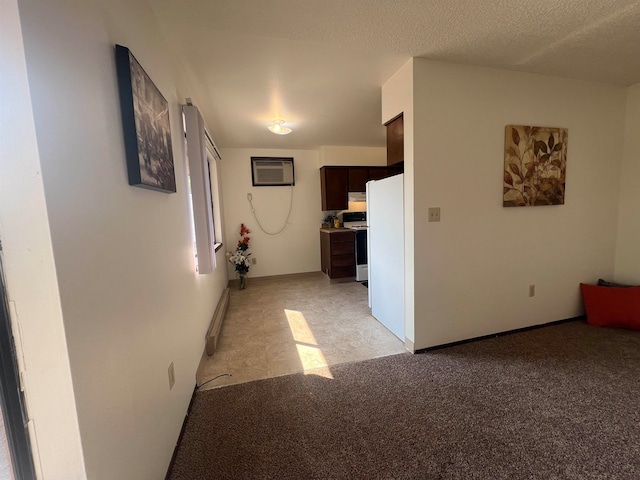 corridor featuring light carpet, a wall mounted AC, and a textured ceiling