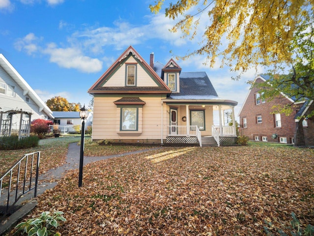 victorian house featuring covered porch and a chimney