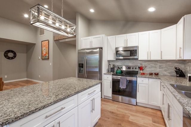 kitchen with lofted ceiling, pendant lighting, white cabinets, and stainless steel appliances