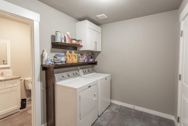 clothes washing area with cabinets and separate washer and dryer