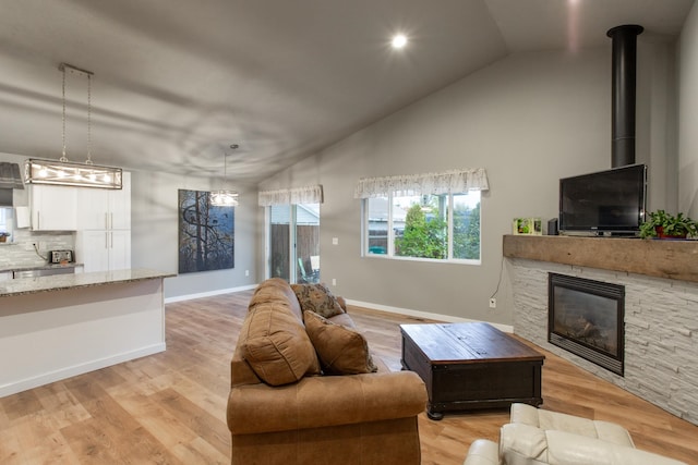 living room with light hardwood / wood-style floors, a fireplace, and vaulted ceiling